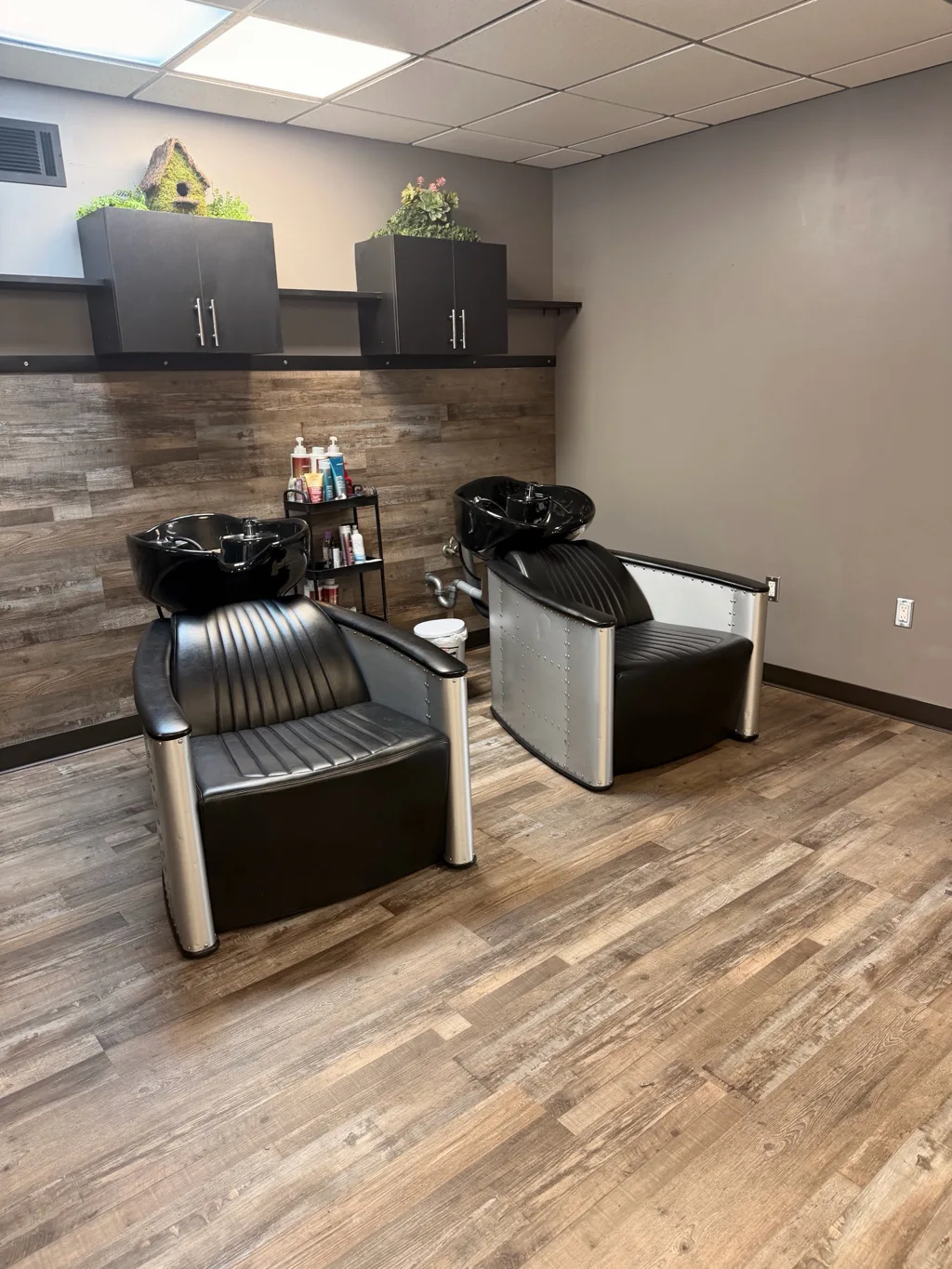 Adjustable shampoo stations with a wood accent wall